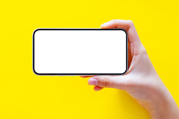 mobile phone horizontally in hand on bright yellow background