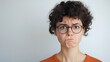 © JorgeL - Portrait of a young woman with an annoyed expression wearing glasses and an orange shirt on a white wall