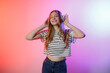 © Sandu - Smiling girl enjoying music with headphones in a colorful backdrop during a cheerful moment