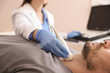 © New Africa - Sonographer conducting ultrasound examination of man's thyroid gland in clinic, closeup