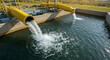 © Iram - Yellow pipes discharging water into a concrete basin at a water treatment facility outdoors view day