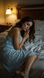 © Em - Ai Generated:Woman in Light Blue Dress Sitting on Bed with White Sheets in Dimly Lit Cozy Room