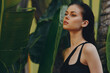 © SHOTPRIME STUDIO - Tropical vibes woman standing in front of lush palm trees and plants in a black tank top