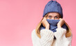 © Prostock-studio - Enigmatic blonde girl hiding from winter cold over pink background, covering face with scarf, free space