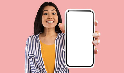 Great Mobile Offer. Excited Asian Lady Showing Big Smartphone With Empty Screen To Camera Advertising New Application For Phone Standing On Pink Studio Background. Mockup