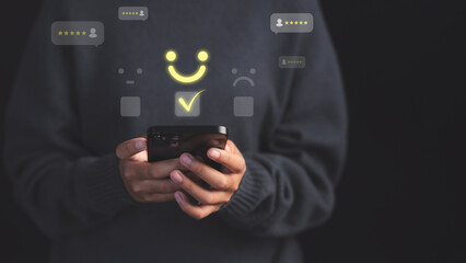 Poster - Female customer using a smartphone select a happy face icon on digital feedback. Concept of customer satisfaction, testimonial, online reviews, user feedback, review rankings and service quality.