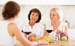 © JackF - Girlfriends chatting and drinking wine at home party table in kitchen