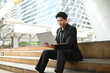 © Stella 16 - A man in a suit is sitting on a set of stairs with a laptop in front of him. He is working or studying, as he is focused on the screen.