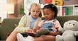© Nina2025/peopleimages.com - Girls, reading or sofa with book for education, learning or story time together at elementary school. Children, kids or students with novel on couch for childhood development, fiction or imagination