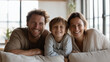© Frenza - modern family (father, mother, young son) relaxing together on a minimalist beige sofa in a bright modern living room
