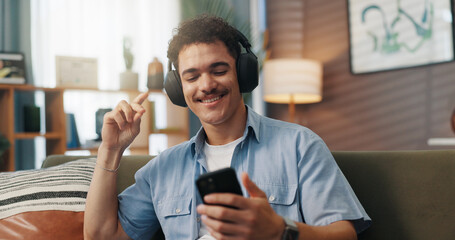 Aufkleber - Phone, man and dancing with headphones on sofa for audio subscription, music playlist and weekend break. Relax, person and happy with internet connection in home for radio app, podcast or sound track