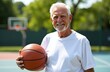 © makanna - Elderly white european man, senior coach holding basketball in hand, wearing t-shirt, stand on outdoor court, sunny day background