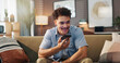 © peopleimages.com - Speaker phone, smile and man in home for communication, story and recording audio message for news. Voice note, mobile and person on sofa for call with contact, talking and question for ai assistant
