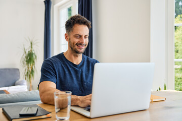 Portrait of handsome mid adult man using laptop at home
