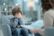 © schmidt - A young adoption counselor is shown supporting a sad little boy by displaying a drawing of a house as he waits for a new loving family to adopt him, with a child psychologist also working with the