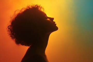 Aufkleber - Silhouette of a woman with curly hair against a vibrant colorful background during an artistic lighting display