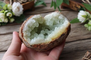 Poster - Beautiful green crystal geode held in hand, surrounded by natural decor and flowers