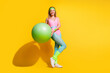 © deagreez - Young woman with exercise ball on vibrant yellow background showcasing active lifestyle and fitness