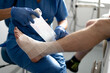 © Carmen - Nurse bandaging patient's injured ankle in hospital room