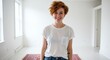 © Lua - A smiling redhead woman stands in a bright, empty room, enjoying the moment with positivity.