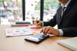 © PSG - Business team analyzing financial charts and graphs using calculator during a meeting in the office