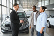 © Serhii - Car salesman showing new car to african american couple in dealership