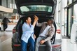 © Serhii - Happy african american couple giving high five celebrating new car purchase at dealership