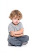© IceSiCool Studio - Sad young child sitting cross-legged with arms folded, looking down, on a white background.