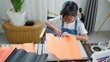© FAMILY STOCK - Asian girl focused on making a DIY craft project at home using a compass and colorful paper, promoting creativity, fine motor skills, and fun learning in a homeschool setting.