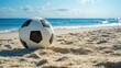 © PixMarket - Classic black and white soccer ball resting on sandy beach with blue ocean and horizon in background