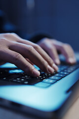 a man in a dark hoodie uses a laptop at night, symbolizing cybercrime, hacking, identity theft, and 