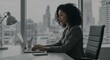 © SRD - Focused businesswoman working on laptop in modern office overlooking city skyline.  Productivity, success, and ambition reflected in her focused work.