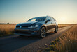 © Pungkas - Modern black hatchback car driving on a rural road during golden hour with scenic fields