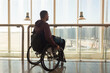 © 24K-Production - Man with disability using wheelchair waits at the airport terminal, gazing out of large windows at the runway. The atmosphere is bright and modern, making travel accessible.