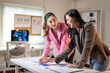 © Wasana - Two women are sitting at a table looking at a chart