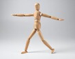© LIGHTFIELD STUDIOS - A wooden artist mannequin balances with arms outstretched in a neutral studio.