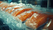 © Nishat - Close-up of a salmon fillet in plastic wrap being packed into transparent bags at a fish factory, a food industry concept.