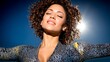 © Nataliya - Woman with curly hair enjoying sunlight with her eyes closed and a smile on her face