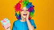 © Yevhen - Little boy hold big present box receive gift. Smiling little boy in clown wig holds gifts in hands