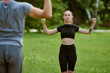 © TRAVELARIUM - Young woman performing qigong in lush green park. Wearing black sports attire, she focuses intently, with arms poised. Cool lighting enhances serene atmosphere
