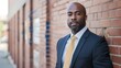 © Chandara - A man in a suit leaning against a brick wall with a serious expression.