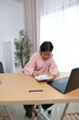 © Wichayada - A girl is sitting at a desk with a laptop and a notebook
