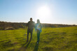 © kinomaster - Young Couple Hiking with Trekking Poles in Open Green Field