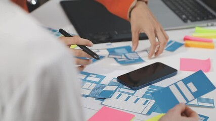 UX/UI designer working on wireframes for a website and mobile app prototype, surrounded by sketches of user-flow and design tools, in concept of website and mobile application design concept.