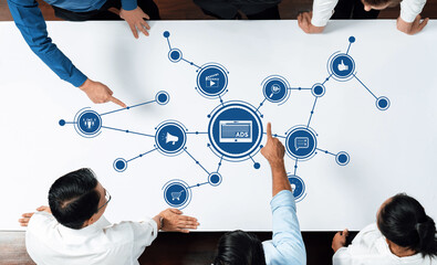 Leinwandbilder - A diverse team collaborates in a meeting, pointing at graphical advertising concepts on a table, showcasing teamwork and strategic planning in marketing initiatives. Amity