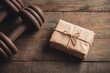 © serdon - On a wooden table near various sports equipment, a black dumbbell is presented as a gift to an athlete, tied with a red bow, representing a commitment to a healthy lifestyle and sports