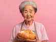 © Maria - Artisan Baker: A portrait of an elderly woman, her gentle smile reflecting the warmth and tradition of home-baked goodness. Holding a loaf of golden bread