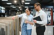 © Serhii - Woman choosing ceramic tiles with shop assistant advising her