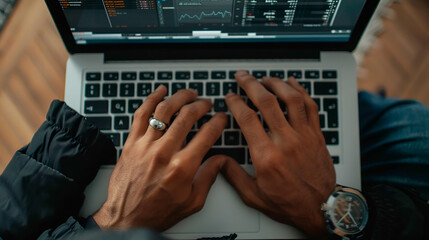 Person typing on a laptop keyboard with code visible on the screen in an indoor setting overhead shot
