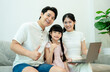 © STOCK88PHOTOGRAPHER - Asian family with a laptop giving the thumbs-up sign, showing approval or success with online learning or shopping.